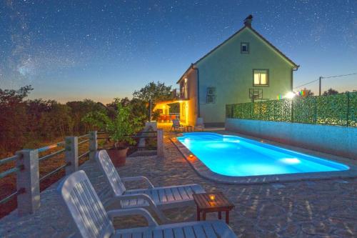 a swimming pool in front of a house at night at Ferienhaus mit Privatpool für 12 Personen ca 202 qm in Lovrec, Dalmatien Dalmatinisches Hinterland in Lovreć