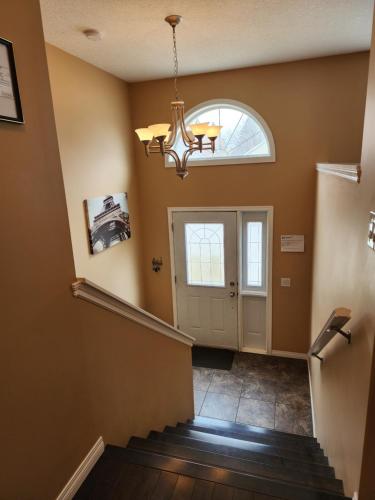 a hallway with a door and a chandelier at Beautiful updated home centrally located, close to General Hospital in Regina