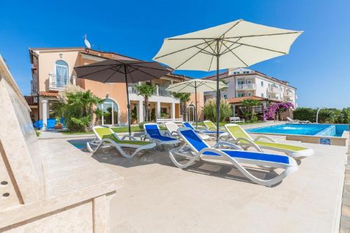 eine Gruppe von Stühlen und Sonnenschirmen neben einem Pool in der Unterkunft Studio für 2 Personen ca 40 qm in Medulin, Istrien Südküste von Istrien - b54338 in Medulin