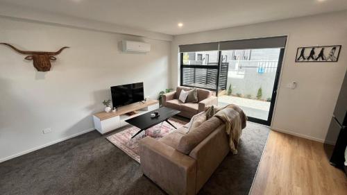 a living room with a couch and a tv at CBD Luxury 2 Bedroom Retreat in Christchurch