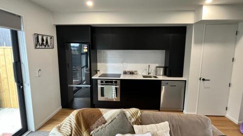 a kitchen with black cabinets and a couch in a room at CBD Luxury 2 Bedroom Retreat in Christchurch