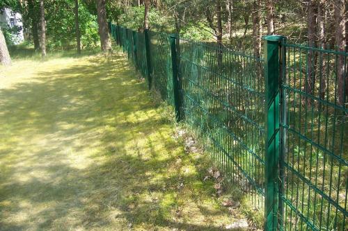 uma cerca verde ao lado de um campo com árvores em Ferienwohnung für 2 Personen 2 Kinder ca 100 qm in Havelaue-Parey, Havelland 