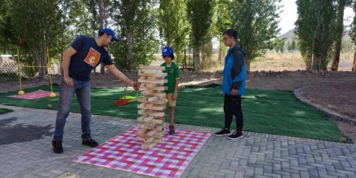 two men and a boy playing a game of dominoes at KaoShan Tent Zhangye in Zhangye