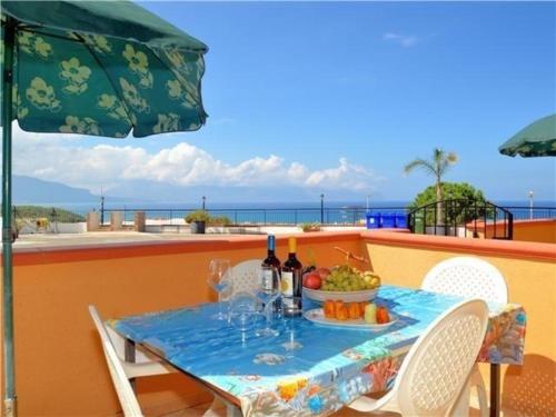 een tafel met een fruitschaal op een balkon met een parasol bij Ferienwohnung für 3 Personen 2 Kinder ca 60 qm in Balestrate, Sizilien Nordküste von Sizilien in Balestrate