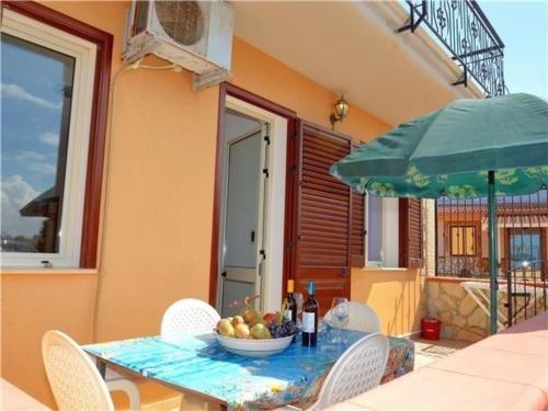 een tafel met een fruitschaal en een groene paraplu bij Ferienwohnung für 3 Personen 2 Kinder ca 60 qm in Balestrate, Sizilien Nordküste von Sizilien in Balestrate