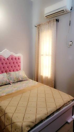 a bedroom with a bed with a pink headboard and a window at Fortune Solar Hotel in Abuja