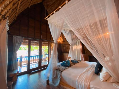 1 dormitorio con 1 cama con cortinas blancas en Harta Lembongan Villas, en Nusa Lembongan