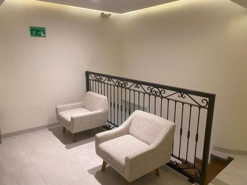two chairs and a chair next to a wall at Hotel Boutique Divino Sol in León