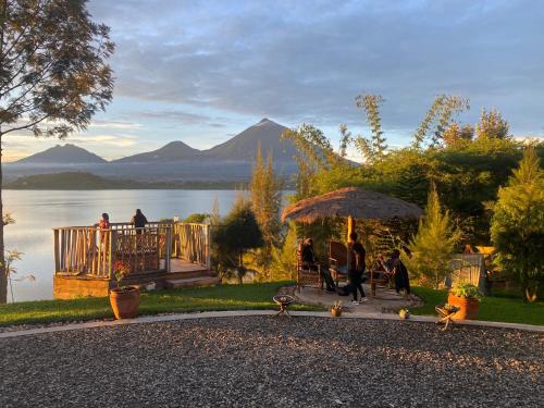 a group of people sitting under an umbrella near a lake at Ruhondo Beach Resort in Ruhengeri