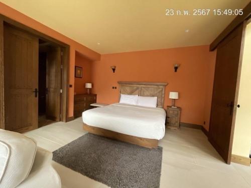 1 dormitorio con cama y pared de color naranja en Toscana Villa Khao Yai en Pak Chong
