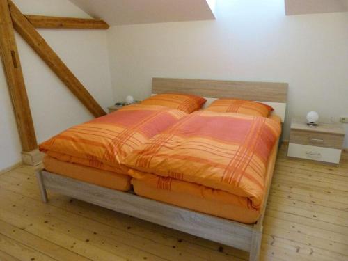 een bed met een oranje dekbed in een slaapkamer bij Kreuzbergblick Bavarian Forest 