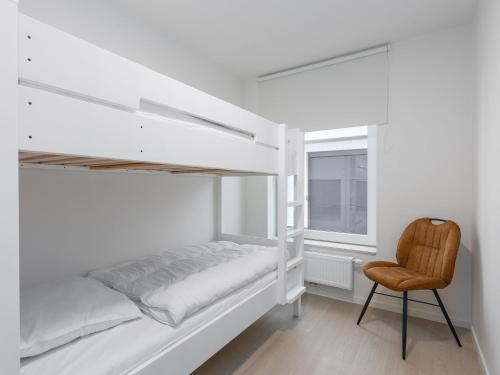 a white bedroom with a bunk bed and a chair at Corner apartment in the center with 3 bedrooms in Middelkerke