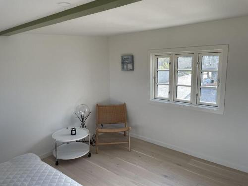 a bedroom with a bed and a chair and a window at Ocean View Modern Retreat in Neksø