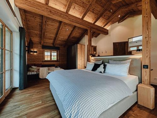 Un dormitorio con una cama grande en una habitación con techos de madera. en Chalet Nordic Modern Retreat, en Bayrischzell