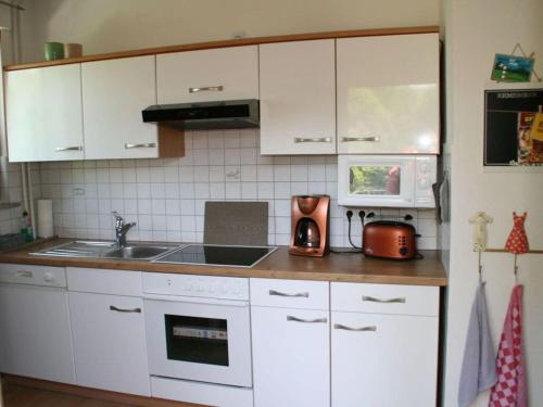 a kitchen with white cabinets and a sink at Modern retreat by the lake in Olsberg