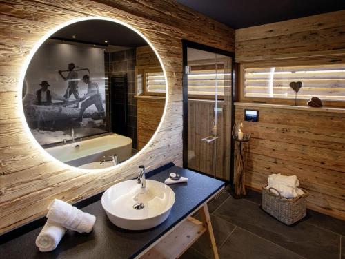 a bathroom with a sink and a mirror and a tub at Alpglück Chalet Modern retreat in Oberstdorf