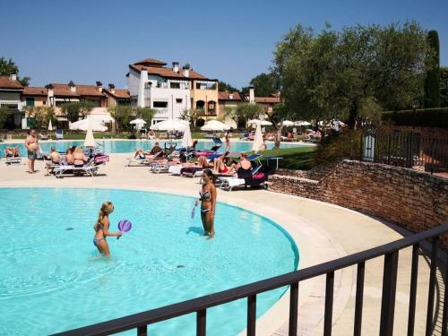 2 personnes jouant au frisbee dans une piscine dans l'établissement Lugana Residence We LAKE it, à Peschiera del Garda