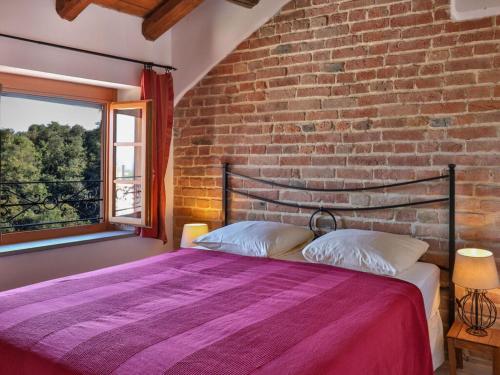 een bed in een kamer met een bakstenen muur bij Dolcetto at Villa Pesce in Mombaruzzo