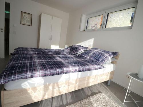 ein Bett mit einer karierten Decke und Kissen darauf in der Unterkunft Haus Edith Modern retreat in Lug