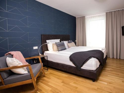a bedroom with a large bed and a chair at Säntis Modern retreat in Friedrichshafen