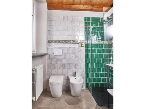 een badkamer met een toilet en een groene betegelde muur bij Catenazzi 2 Modern retreat in Brezzo