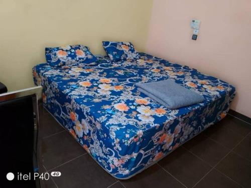 uma cama num quarto com um cobertor azul com flores em Oluwa-Sheyi Apartment in Ketou em Kétou