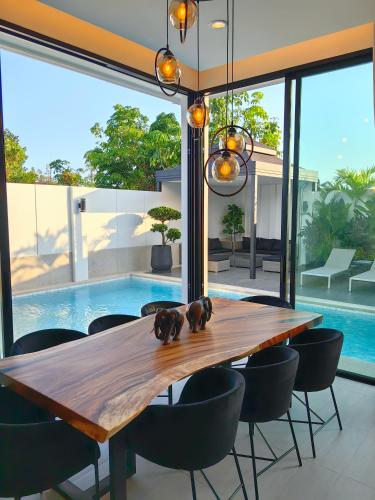 a dining room with a wooden table and chairs and a pool at Bangtao Luxury Pool Villa - Prymana in Phuket