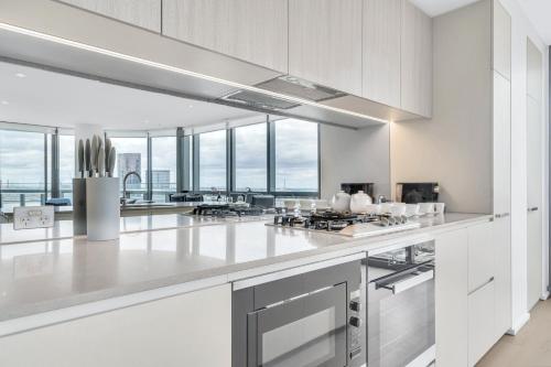a large kitchen with white cabinets and windows at Melbourne Lifestyle Apartments - Best Views on Collins in Melbourne