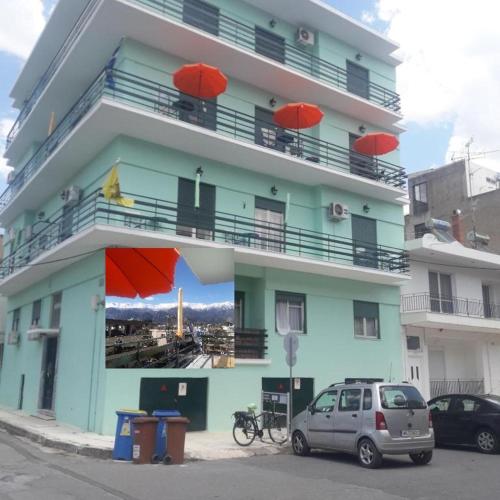a blue building with red umbrellas in front of it at Hellas Palace Rooms CENTER in Sparti