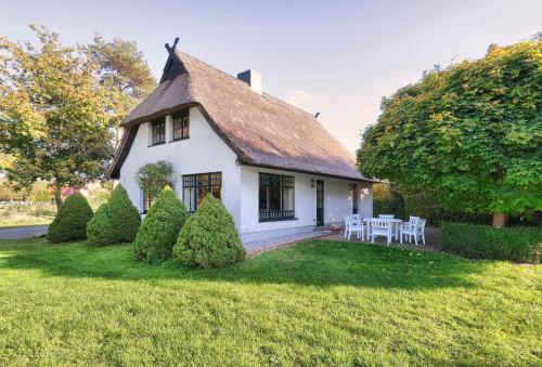 a white house with a table and chairs in the yard at Reetdachhaus mit großem Garten und Kamin in Marlow