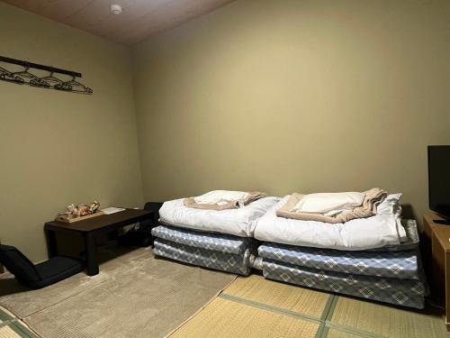 a room with a bed and a table in it at Wafu Ryokan Uehonmachi in Osaka