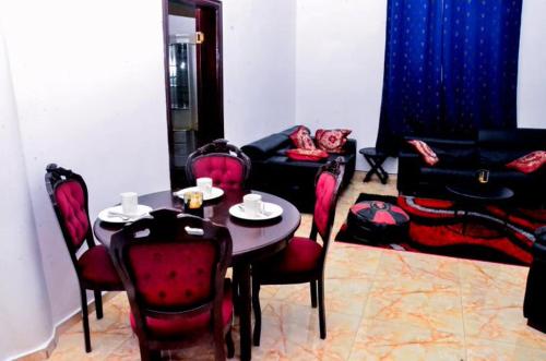 a dining room with a table and red chairs at Sunu Sal Apartment in Kololi