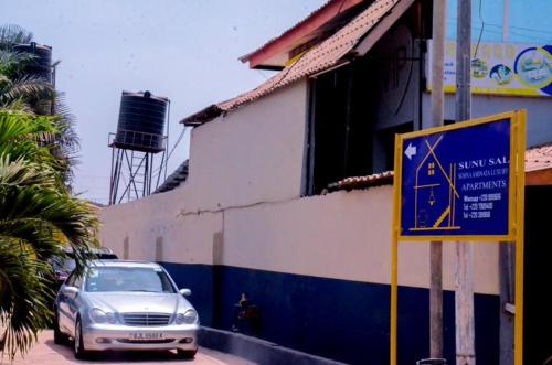 a car parked next to a building with a sign at Sunu Sal Apartment in Kololi