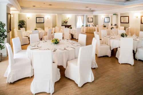 a room filled with white tables and white chairs at Hotel Concord in Turin