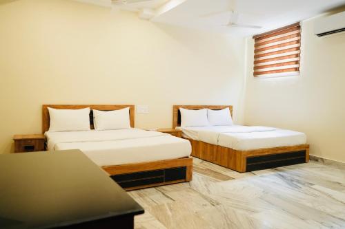 Zimmer mit 2 Betten und einem Tisch in der Unterkunft Kalanad Residency in Kalanādu