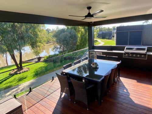 eine Terrasse mit einem Tisch und Stühlen sowie einem großen Fenster in der Unterkunft Stunning Lakeside Villa in River Front Resort with Pool in Moama