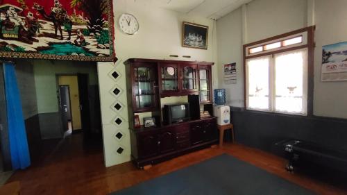 - un salon avec une télévision et une horloge murale dans l'établissement Mudhahar Homestay Syariah, à Baso