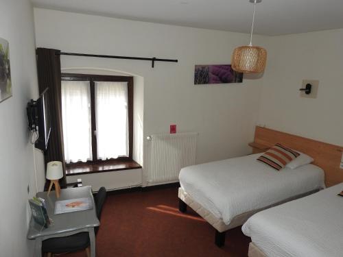 a hotel room with two beds and a window at Le Barriol in Saint-Julien-Chapteuil