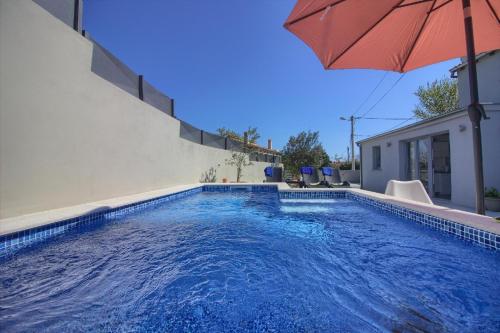 a swimming pool with an umbrella next to a house at Ferienhaus mit Privatpool für 8 Personen ca 80 qm in Ližnjan, Istrien Südküste von Istrien in Ližnjan
