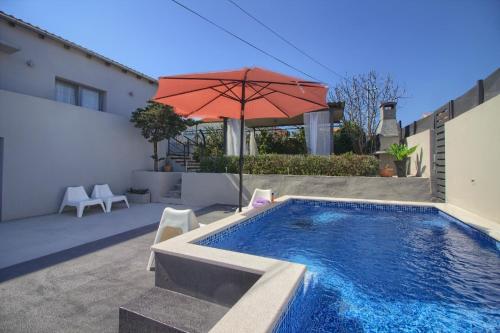 a pool with an umbrella and chairs and a table with at Ferienhaus mit Privatpool für 8 Personen ca 80 qm in Ližnjan, Istrien Südküste von Istrien in Ližnjan