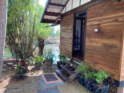 um edifício de madeira com um banco e algumas plantas em Udon Thani Farm Stay Talay Bua Daeng em Ban Non Sung