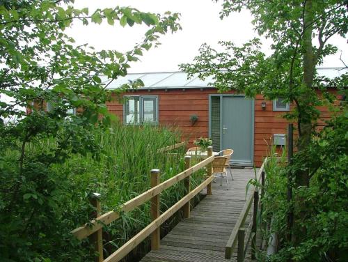einen Holzsteg, der zu einer Hütte mit einem Tisch und Stühlen führt in der Unterkunft Hausboot Schiff für 4 Personen ca 85 m in Oudega, Friesland Küste von Friesland in Oudega