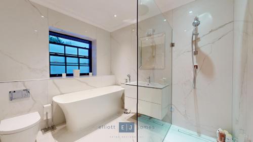 a white bathroom with a toilet and a shower at Grand London suburban mansion in Buckhurst Hill