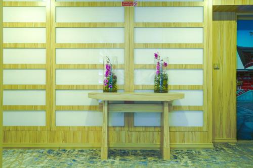 una pared de madera con dos jarrones sobre una mesa en Palette Royal Reflections Hotel and Spa Dubai, en Dubái