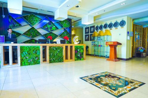 a lobby with a green wall and a counter at Palette Royal Reflections Hotel and Spa Dubai in Dubai