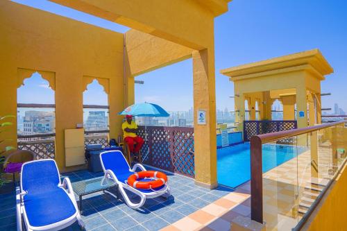 einen Balkon mit Stühlen und einen Pool auf einem Gebäude in der Unterkunft Palette Royal Reflections Hotel and Spa Dubai in Dubai