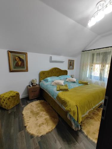 a bedroom with a bed with a yellow blanket and rugs at Black&White House in Ocna-Mureşului