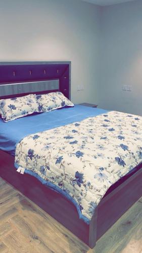 a bed with a blue and white comforter on it at Retal Hotel Apartments in Taif