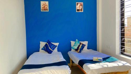 two beds in a room with a blue wall at Z Homes in Shamsgarh