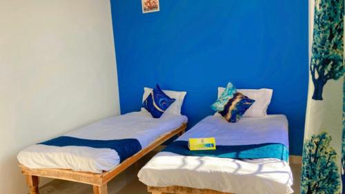 2 Einzelbetten in einem Zimmer mit blauer Wand in der Unterkunft Z Homes in Shamsgarh